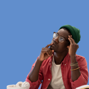 Black man with green hat, glasses, white t-shirt and red shirt is shown against a blue background. He is thinking about having ADHD coaching.